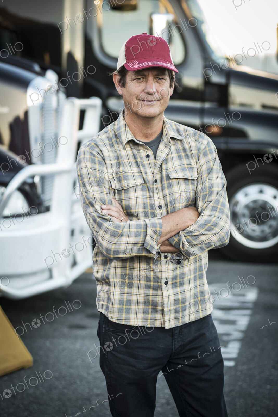 Caucasian man truck driver with his truck parked in a lot at a truck stop.
