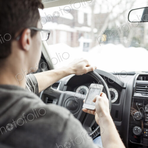 Caucasian man using cell phone and driving car Caucasian man using cell phone and driving car