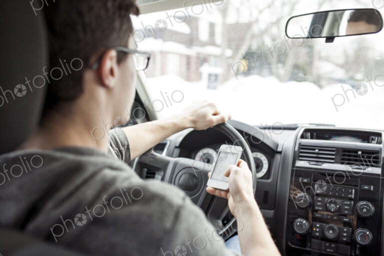 Caucasian man using cell phone and driving car