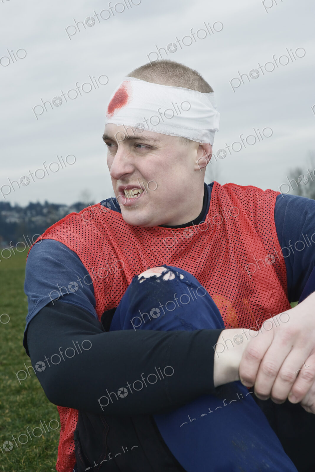 Caucasian man with a bandaged head, a head injury, sitting on the ground.