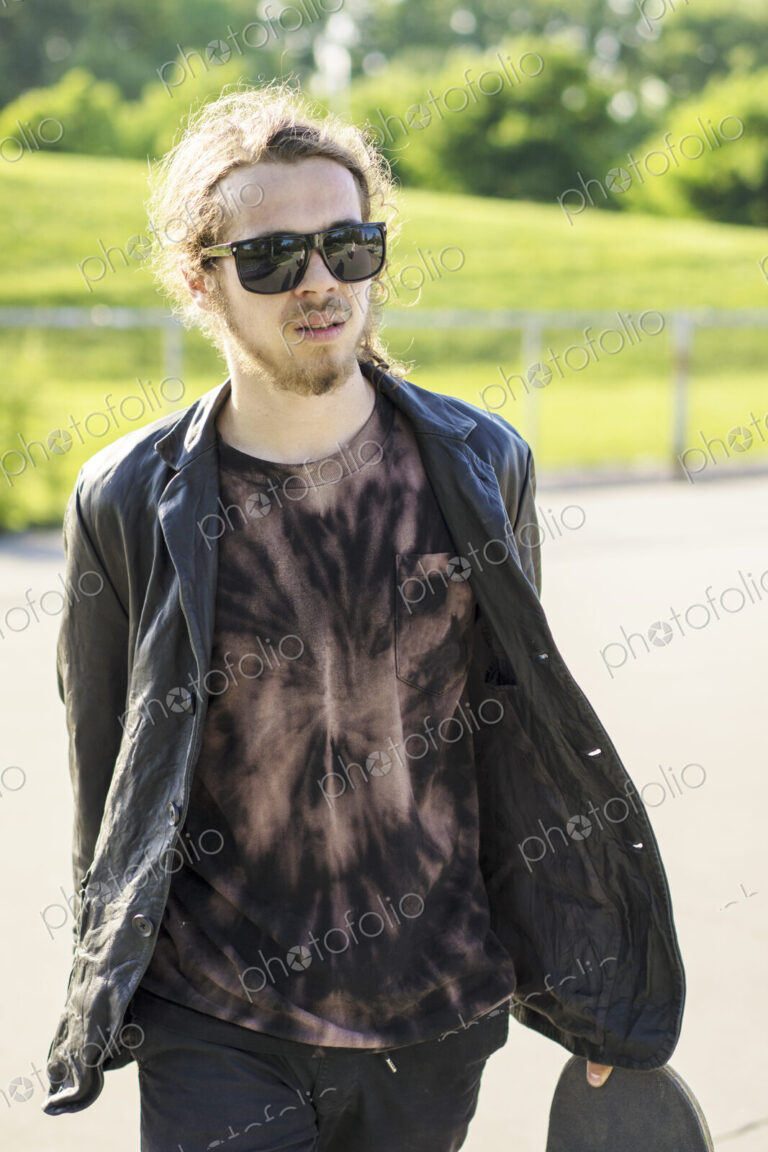 Caucasian man with beard carrying skateboard