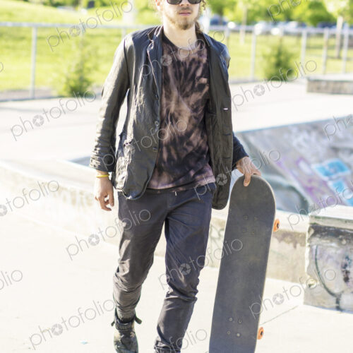 Caucasian man with beard carrying skateboard Caucasian man with beard carrying skateboard