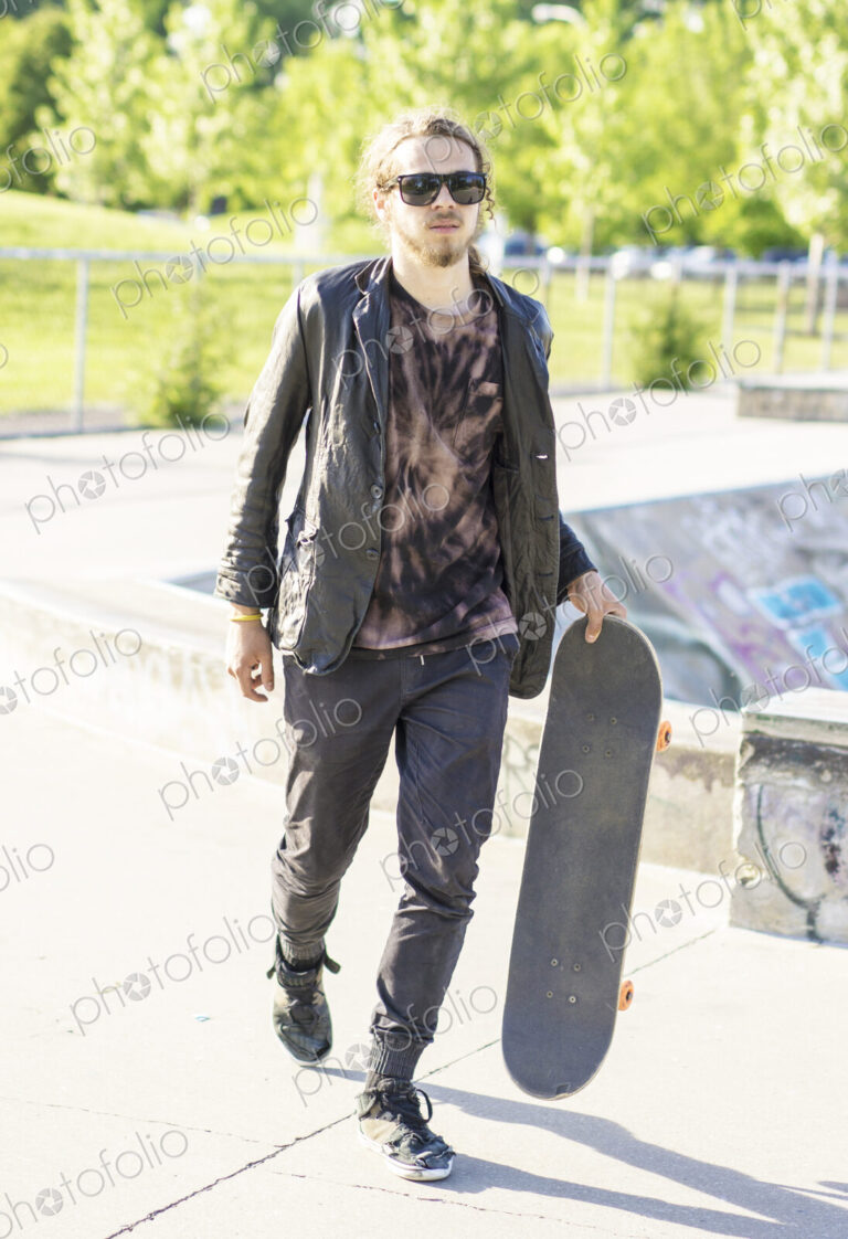 Caucasian man with beard carrying skateboard