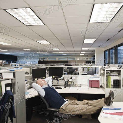 Caucasian man with his feet up on his desk sitting alone at his cubicle desk. Caucasian man with his feet up on his desk sitting alone at his cubicle desk.