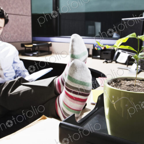 Caucasian man with his feet up working in an office cubicle