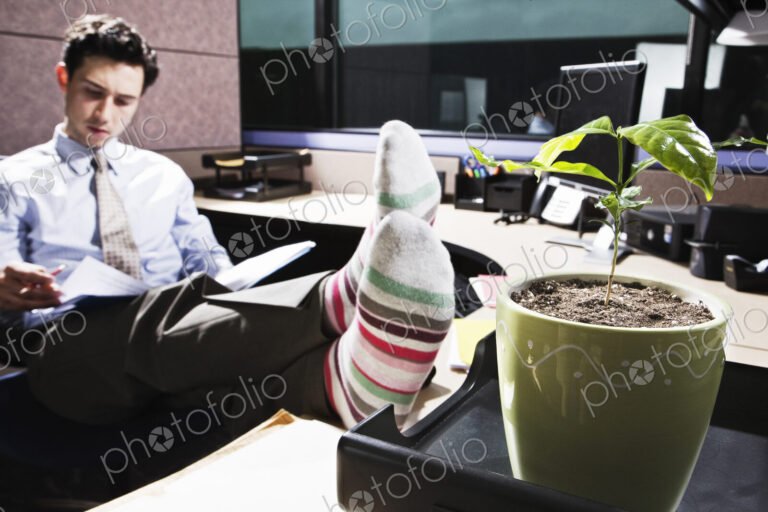 Caucasian man with his feet up working in an office cubicle