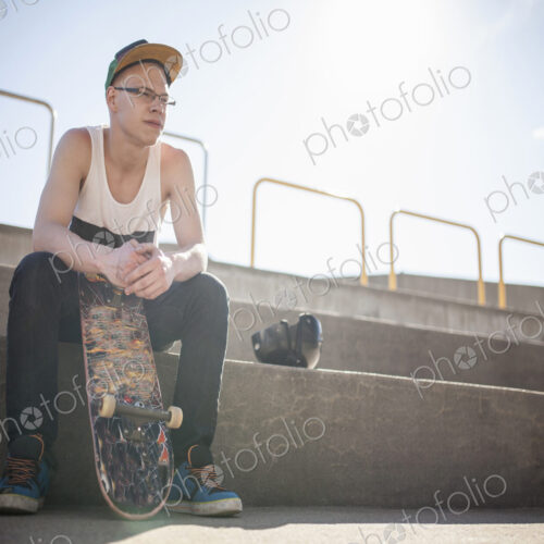 Caucasian man with skateboard sitting on steps Caucasian man with skateboard sitting on steps