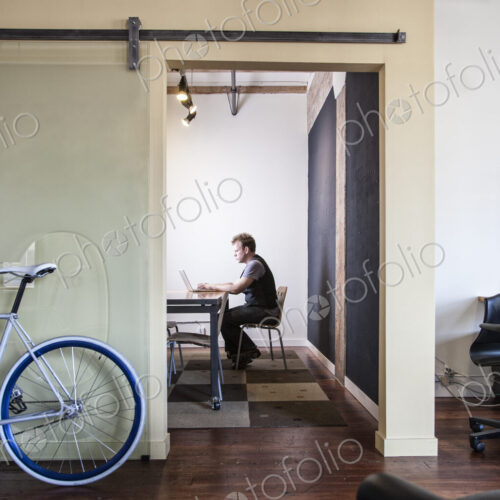Caucasian man working at a laptop computer in a small conference room. Caucasian man working at a laptop computer in a small conference room.