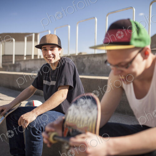 Caucasian men with skateboards sitting on steps Caucasian men with skateboards sitting on steps