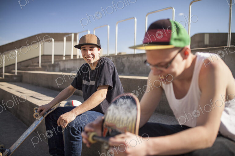 Caucasian men with skateboards sitting on steps