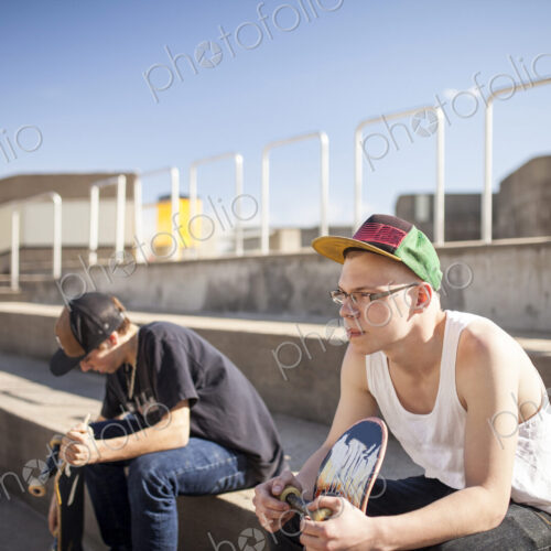 Caucasian men with skateboards sitting on steps Caucasian men with skateboards sitting on steps