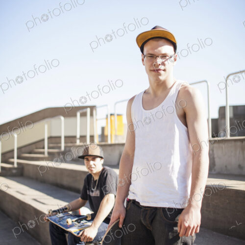 Caucasian men with skateboards sitting on steps