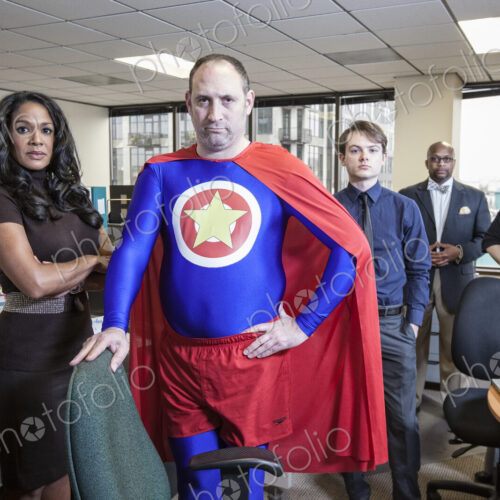Caucasian middle aged man super hero and his mixed race team staff in thieir office Caucasian middle aged man super hero and his mixed race team staff in thieir office