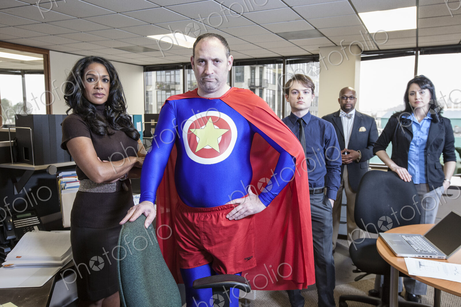 Caucasian middle aged man super hero and his mixed race team staff in thieir office