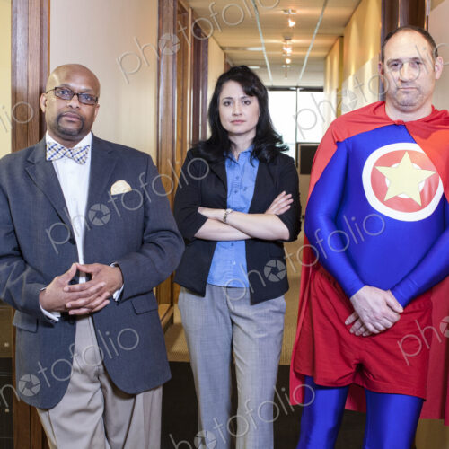 Caucasian middle aged man super hero and his mixed race team staff in thieir office Caucasian middle aged man super hero and his mixed race team staff in thieir office