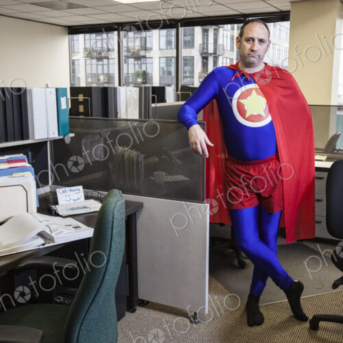 Caucasian middle aged man super hero in his cubicel office. Caucasian middle aged man super hero in his cubicel office.