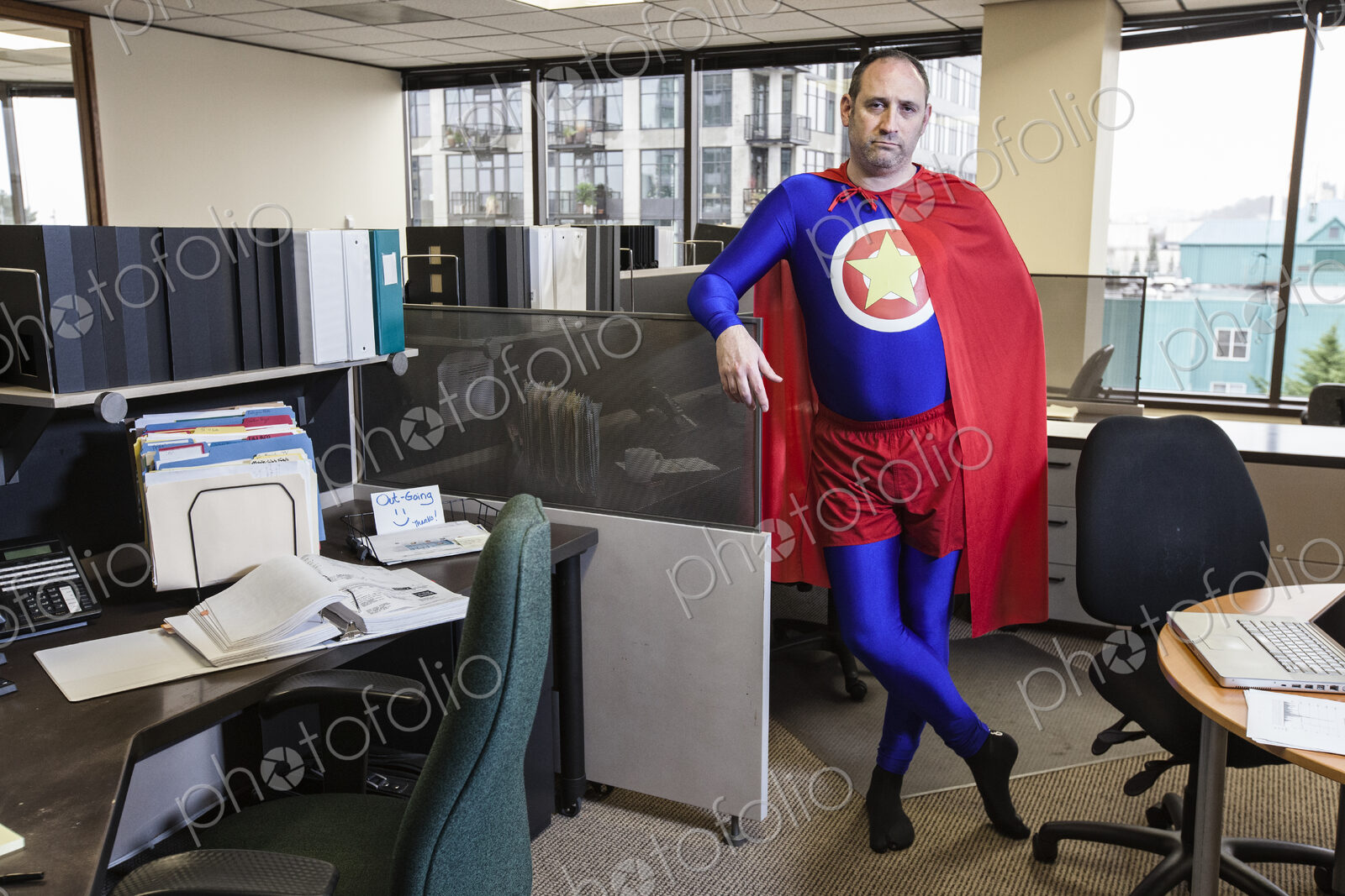 Caucasian middle aged man super hero in his cubicel office.