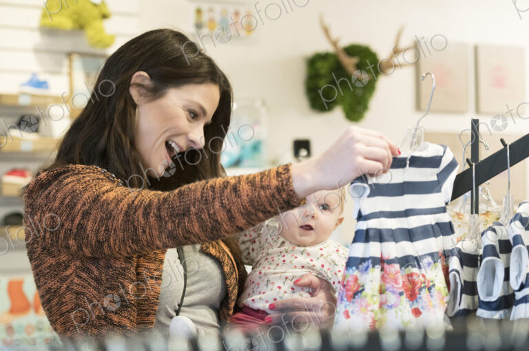 Caucasian mother and baby daughter shopping in clothing store