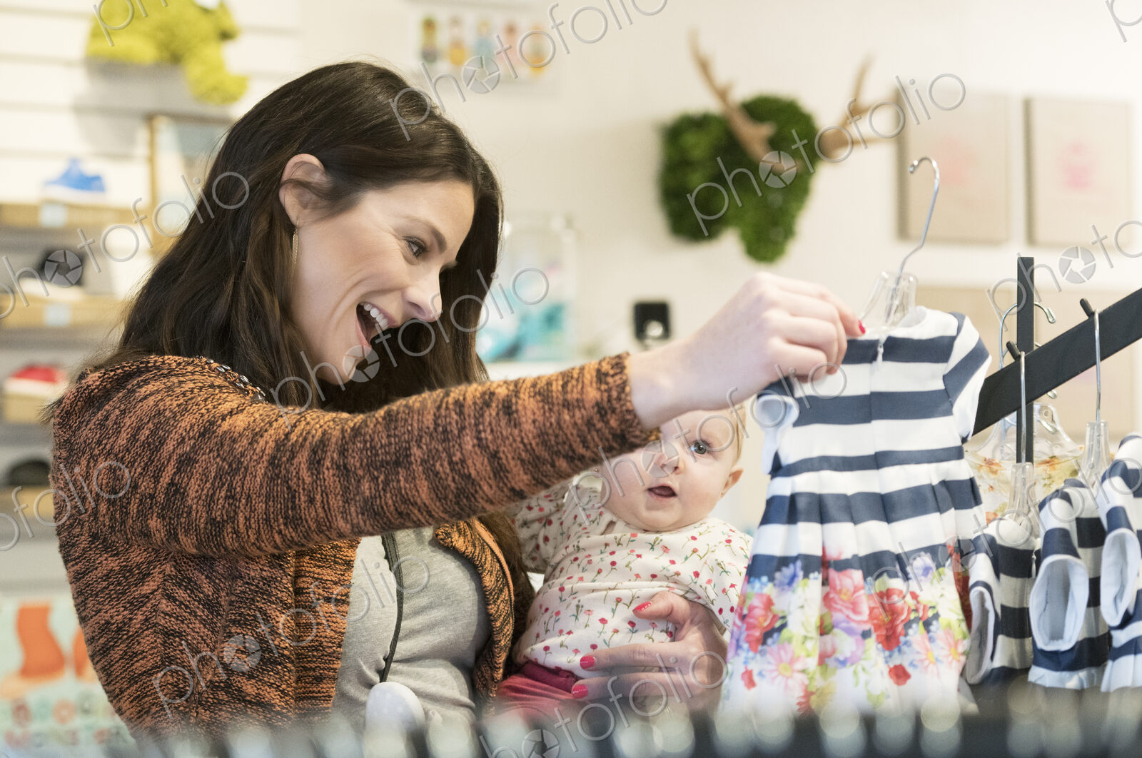 Caucasian mother and baby daughter shopping in clothing store