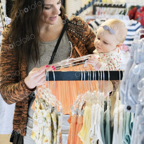 Caucasian mother and baby daughter shopping in clothing store Caucasian mother and baby daughter shopping in clothing store