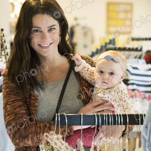 Caucasian mother and baby daughter shopping in clothing store Caucasian mother and baby daughter shopping in clothing store