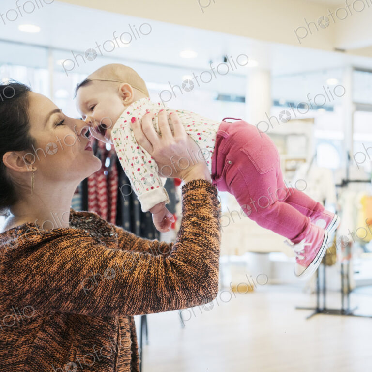 Caucasian mother and baby daughter shopping in store