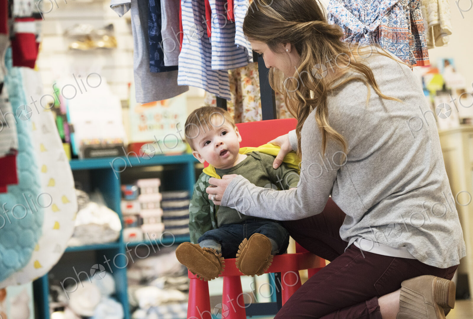 Caucasian mother and baby son shopping in clothing store