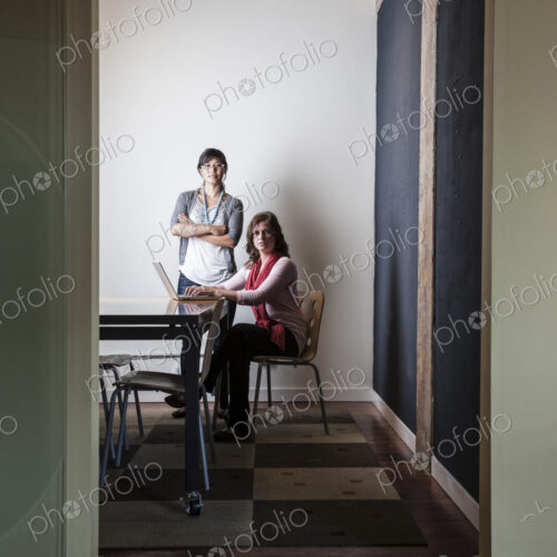 Caucasian woman and Asian woman working on a laptop computer in a small conference room. Caucasian woman and Asian woman working on a laptop computer in a small conference room.