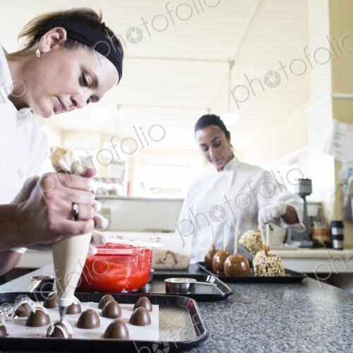 Caucasian woman and Hispanic woman working on creating candy in a candy shop. Caucasian woman and Hispanic woman working on creating candy in a candy shop.