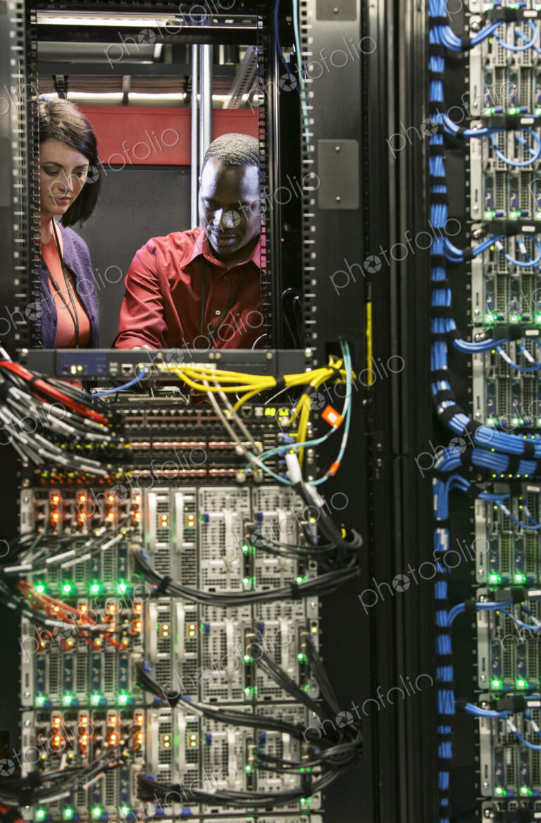 Caucasian woman and black man technicians running diagnostic tests on servers in a…