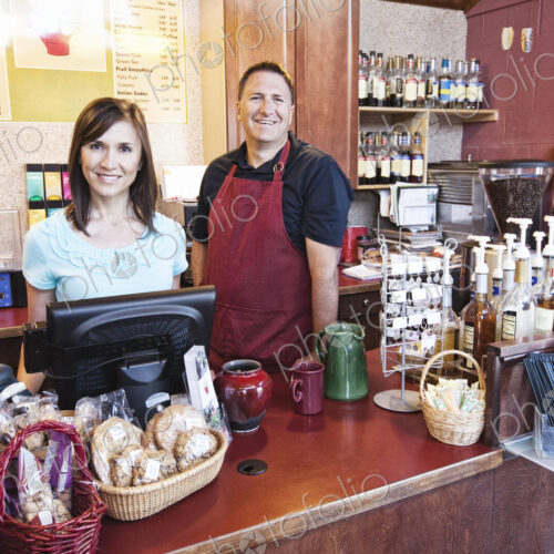 Caucasian woman and man, business owners of a coffee shop, at the counter. Displays of… Caucasian woman and man, business owners of a coffee shop, at the counter. Displays of…