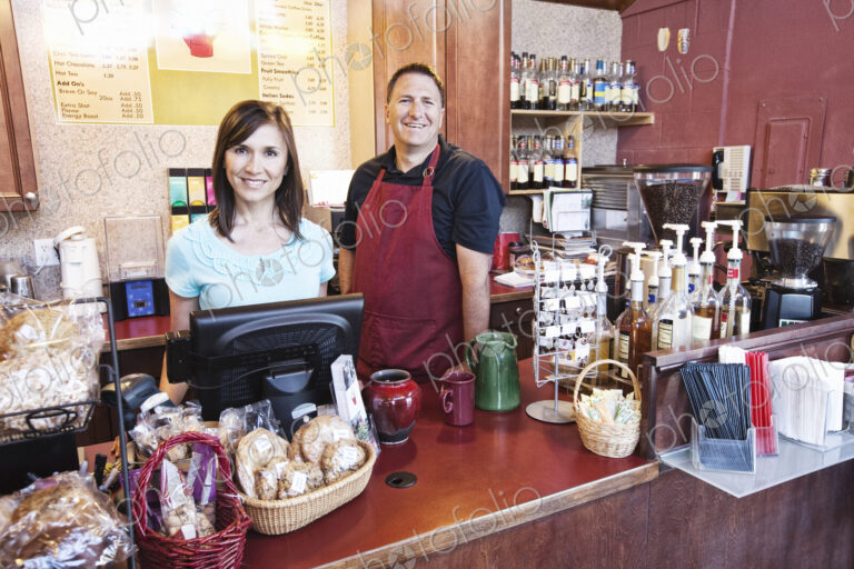 Caucasian woman and man, business owners of a coffee shop, at the counter. Displays of…