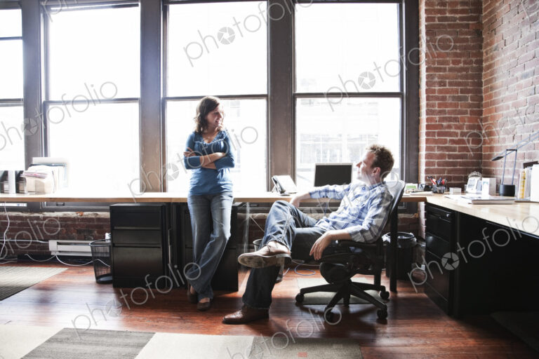 Caucasian woman and man meeting to discuss an issue at a creative office workstation.