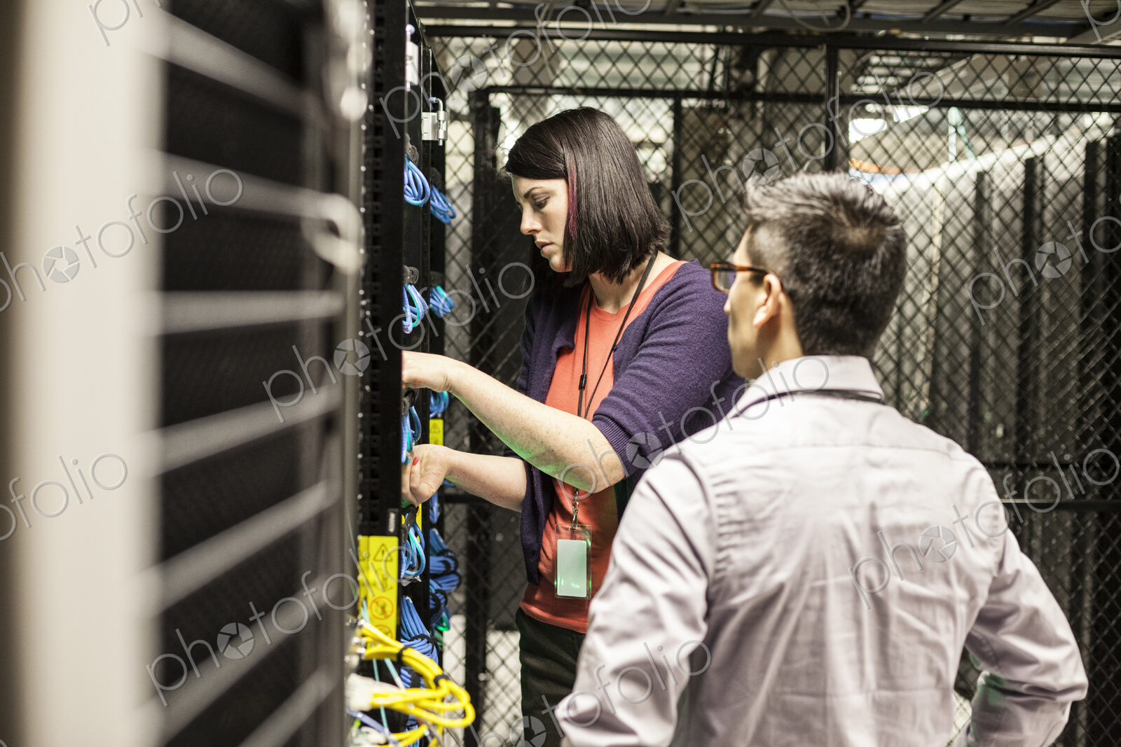 Caucasian woman and man technicians working on CAT 5 cables in a large computer server…