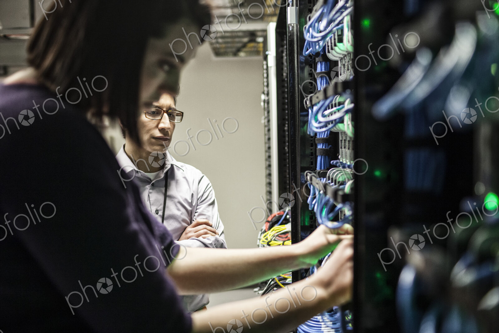 Caucasian woman and man technicians working on CAT 5 cables in a large computer server…