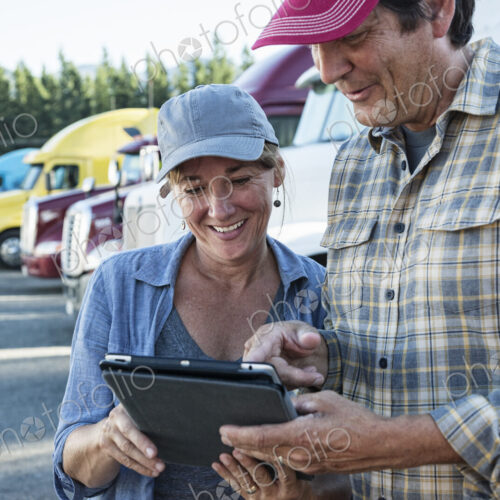 Caucasian woman and man truck driving team working on their driving log in a truck… Caucasian woman and man truck driving team working on their driving log in a truck…
