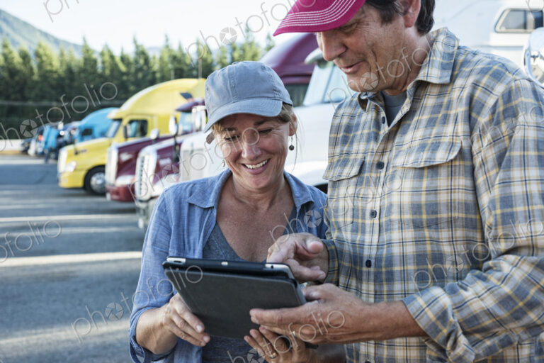Caucasian woman and man truck driving team working on their driving log in a truck…