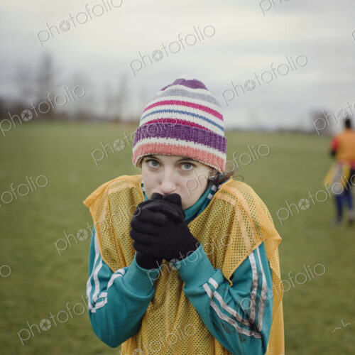 Caucasian woman blowing on her hands to stay warm at a sporting event in the winter. Caucasian woman blowing on her hands to stay warm at a sporting event in the winter.