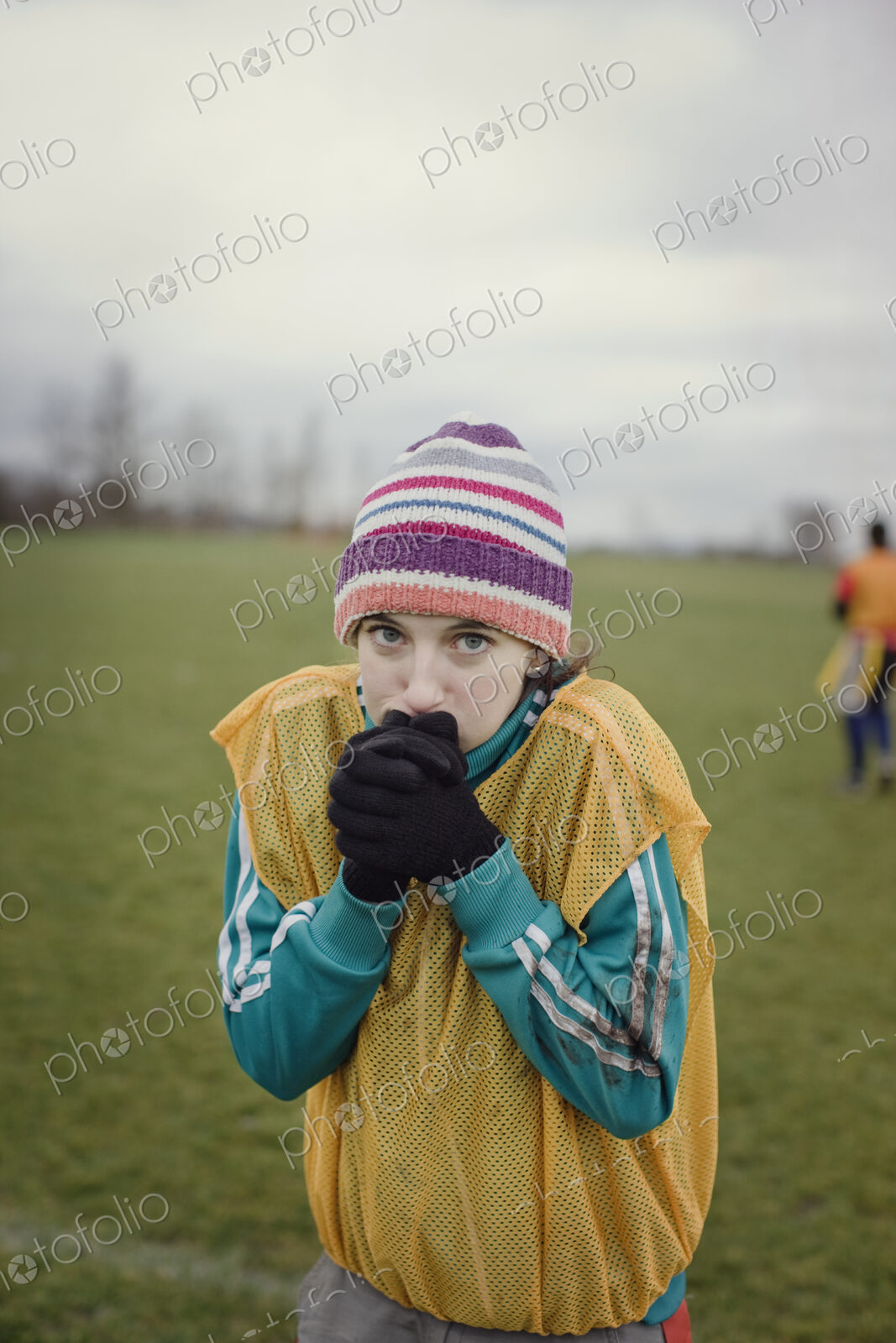 Caucasian woman blowing on her hands to stay warm at a sporting event in the winter.