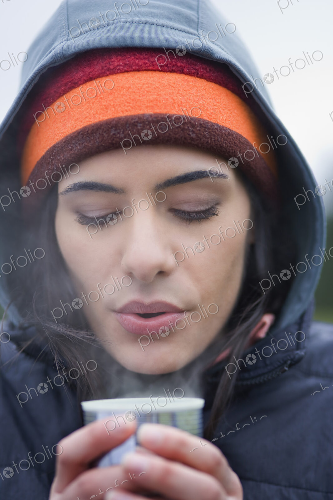 Caucasian woman blowing on the surface of a hot cup of coffee on a winter day.