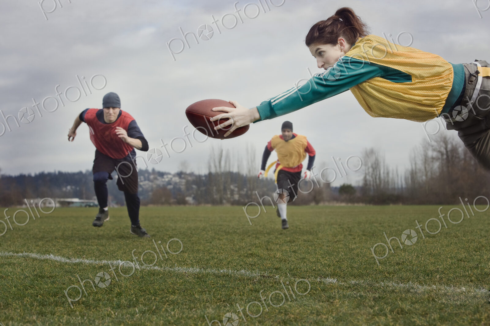Caucasian woman diving with a football during a non-contact flag football match.
