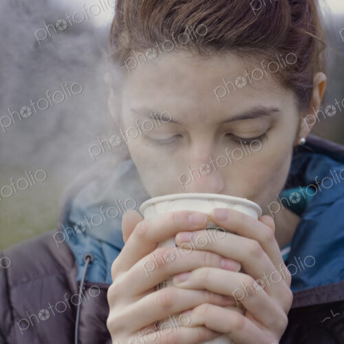 Caucasian woman drinking a hot cup of coffee on a winter day.