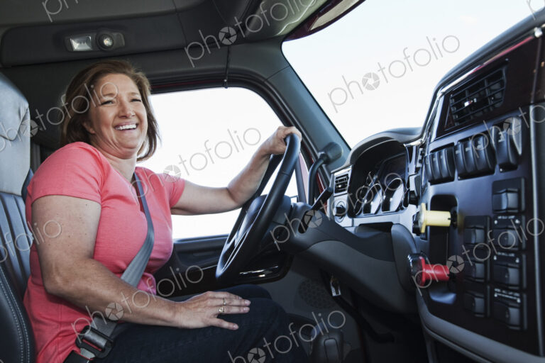 Caucasian woman driver in the cab of a commercial truck.