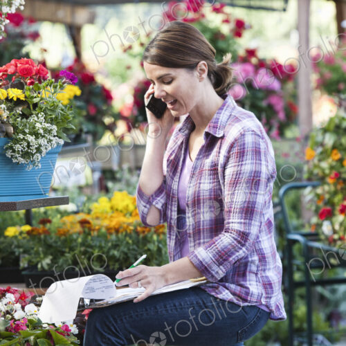 Caucasian woman employee of a nursery ordering supplies on the phone. Caucasian woman employee of a nursery ordering supplies on the phone.
