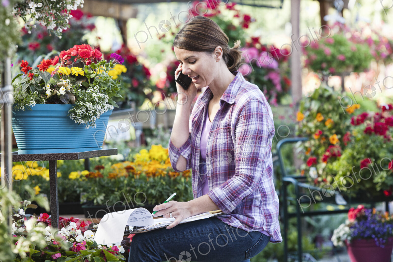 Caucasian woman employee of a nursery ordering supplies on the phone.