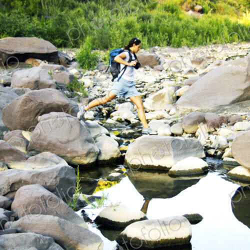 Caucasian woman jumping on rocks in river Caucasian woman jumping on rocks in river