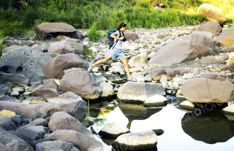 Caucasian woman jumping on rocks in river