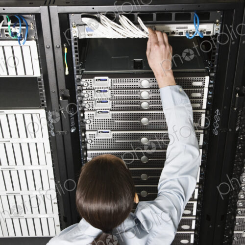 Caucasian woman lab technician working on servers in a computer sever farm. Caucasian woman lab technician working on servers in a computer sever farm.