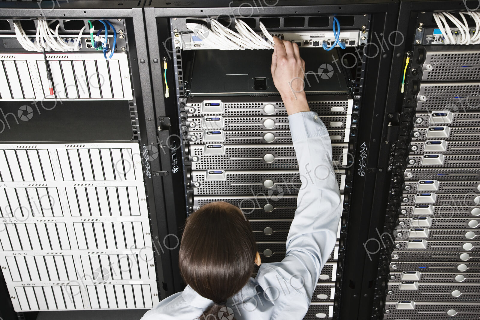 Caucasian woman lab technician working on servers in a computer sever farm.
