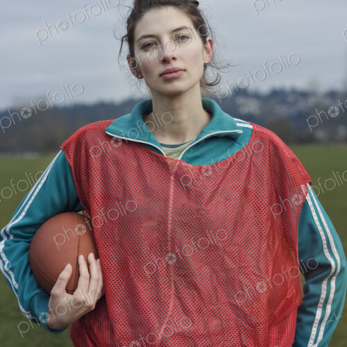 Caucasian woman member of a non-contact flag football team holding a football.